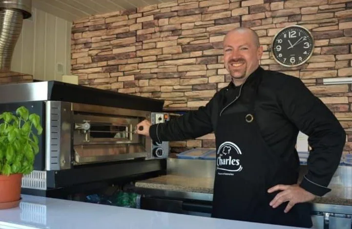 Charles, artisan pizzaiolo, à côté de son four